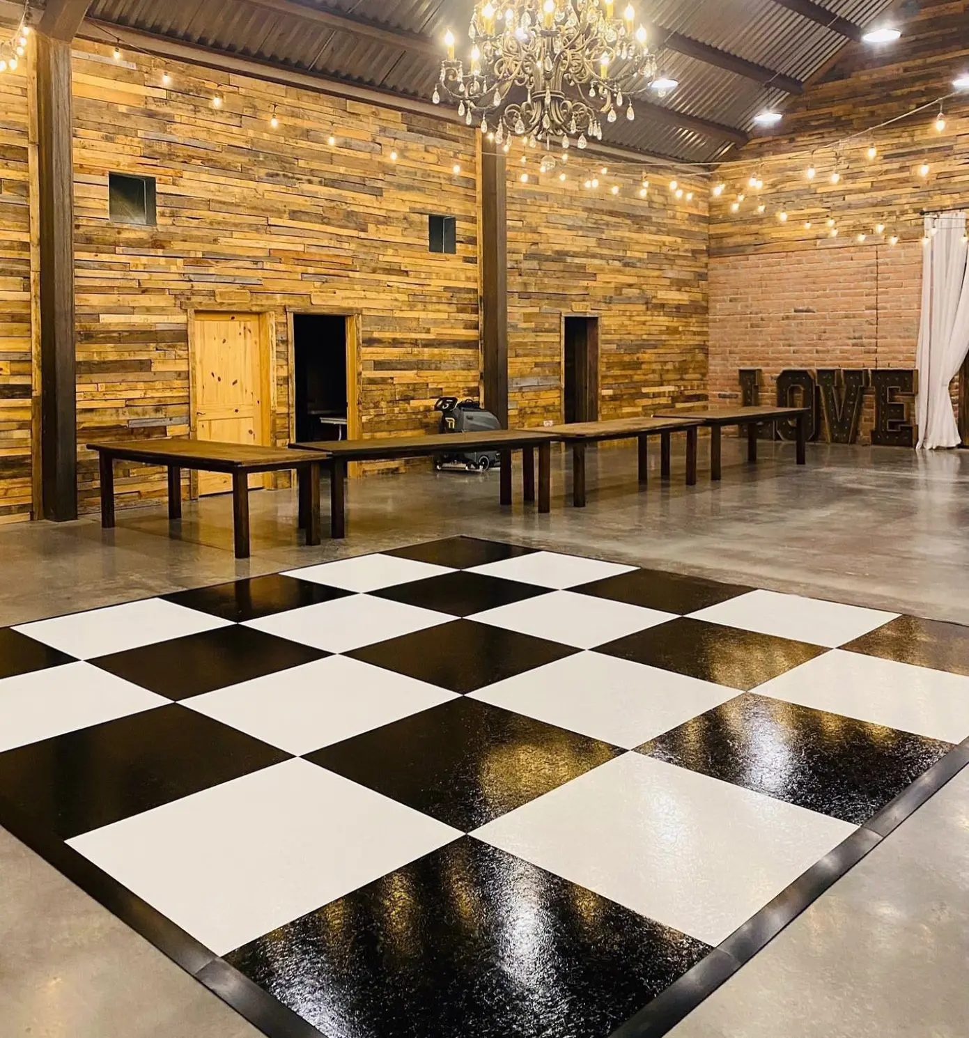 Black and white dance floor rental in a rustic indoor venue